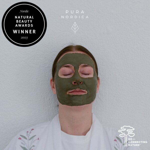 Naisen kasvoilla tummanvihreä savinaamio, kuvan yläosassa teksti Nordic Natural Beauty Awards Winner 2023 sekä yrityksen logo, jossa teksti PURA NORDICA ja lehti. Kuvan alanurkassa teksti Re-Connecting Nature