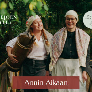 Kaksi vanhan ajan vaatteisiin pukeutunutta naista kulkevat vierekkäin, toisella peilari kädessä.